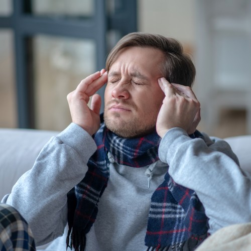 Kopfschmerzen. Mann kämpft mit Kopfschmerzen und hohem Fieber.